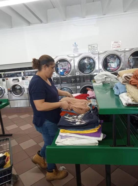 Tia washing and folding donated clothing at a laundromat.