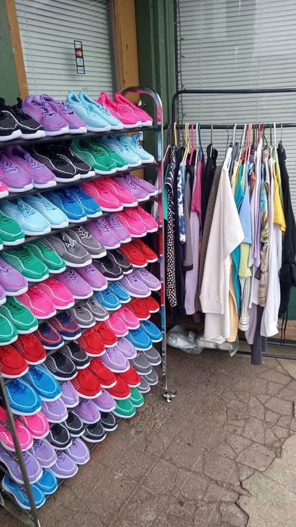 A rack of colorful sneakers beside a clothing rail.